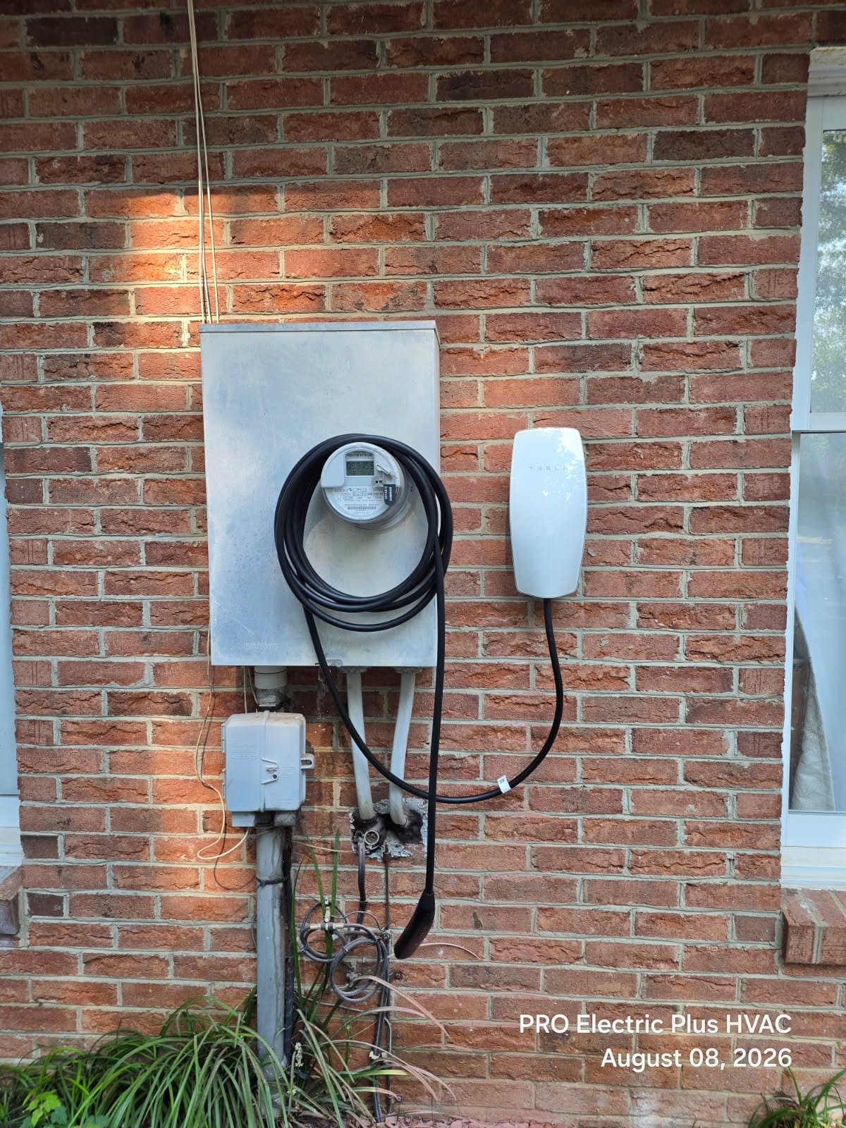 An EV charger installed next to the electric meter on a home exterior